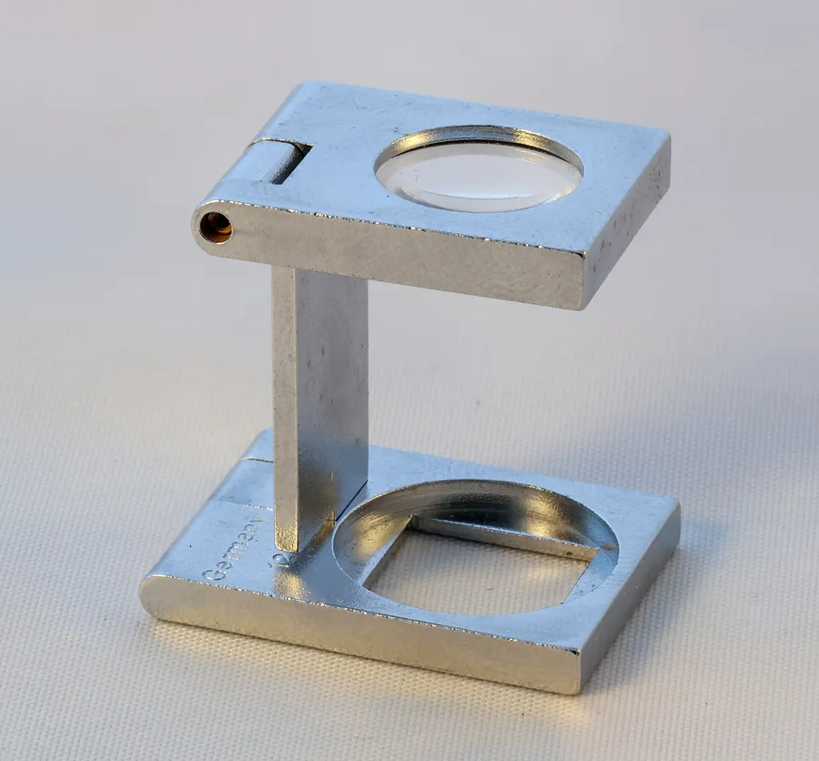 Un compte-fils en métal, petite loupe pliante grossissant dix fois, utilisée pour examiner de près un tissu ou une impression