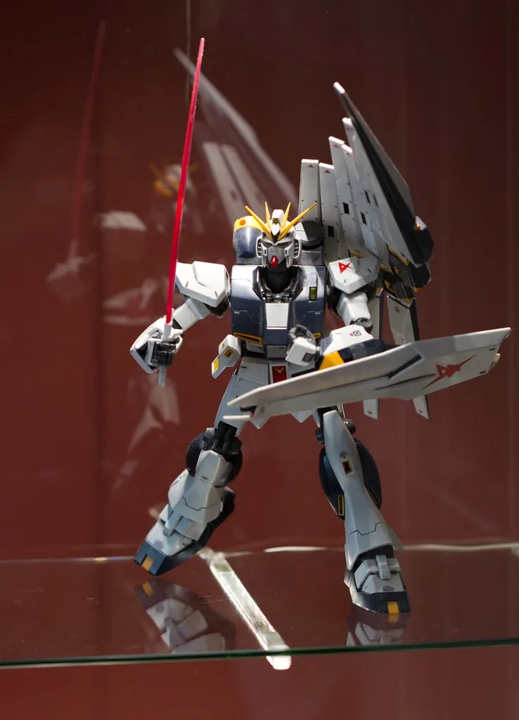 Une maquette de Gundam RX-93 posée sur une tablette en verre, à l'intérieur d'une vitrine IKEA DETOLF