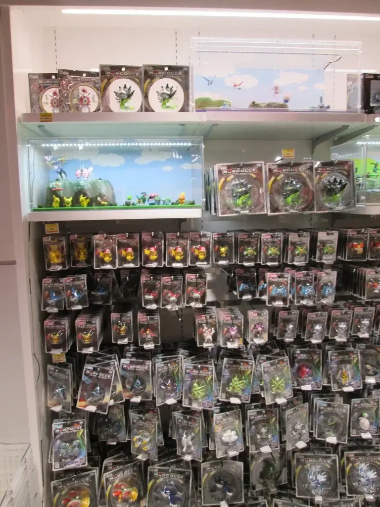 Mur de petites figurines Pokémon Moncolle en blister, avec deux dioramas vitrés, au Mega Tokyo Pokémon Center d'Ikebukuro