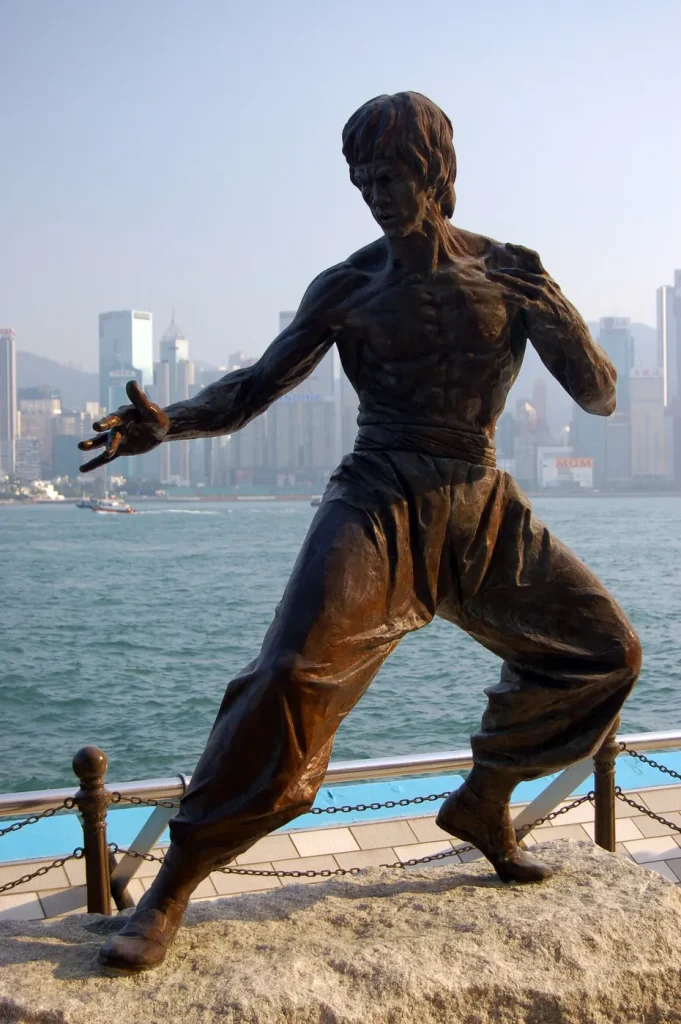 Statue en bronze de Bruce Lee en garde de kung-fu sur l'Avenue of Stars de Hong Kong, la baie Victoria en arrière-plan
